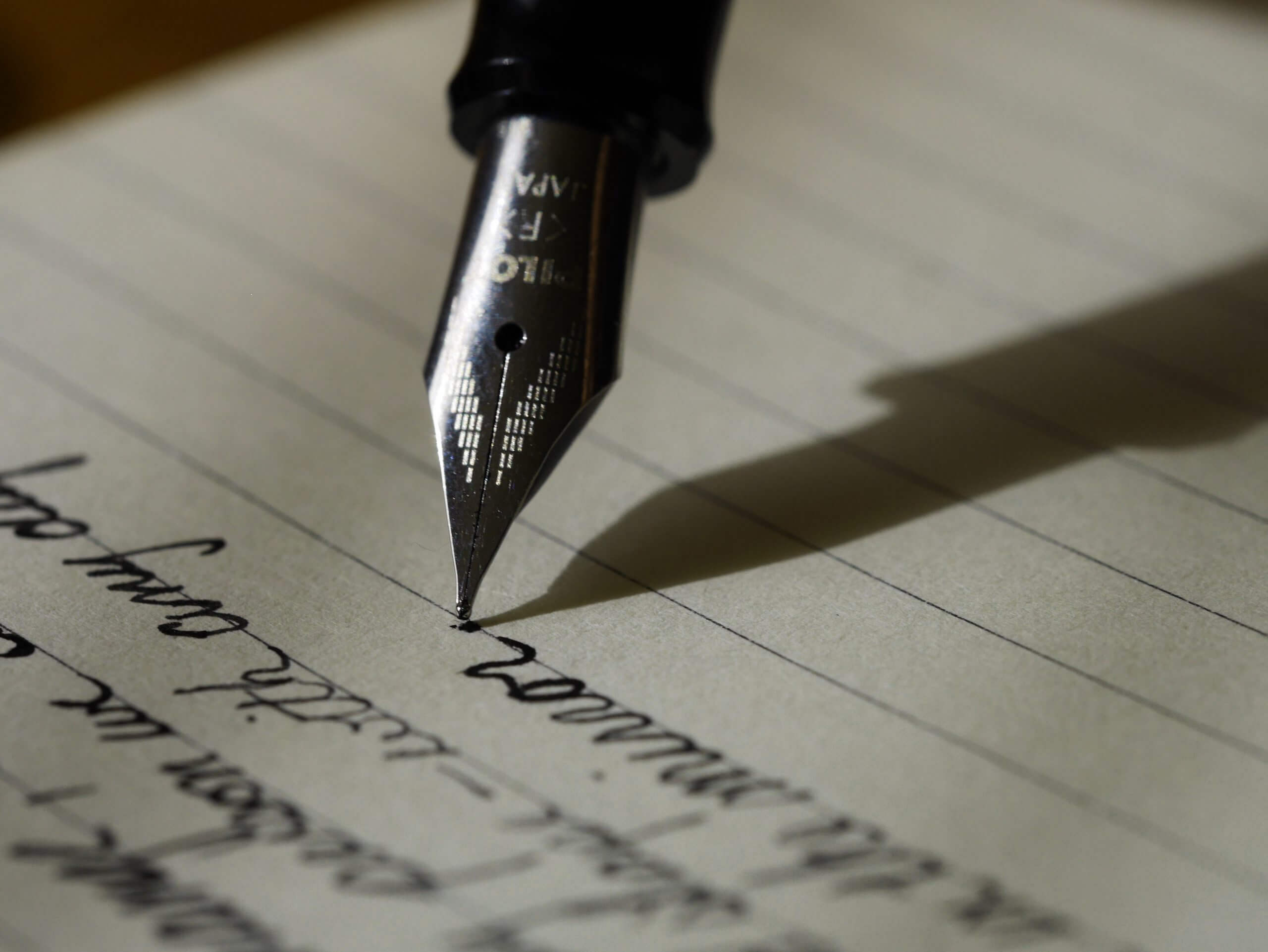 Fountain pen writing cursive script on lined paper