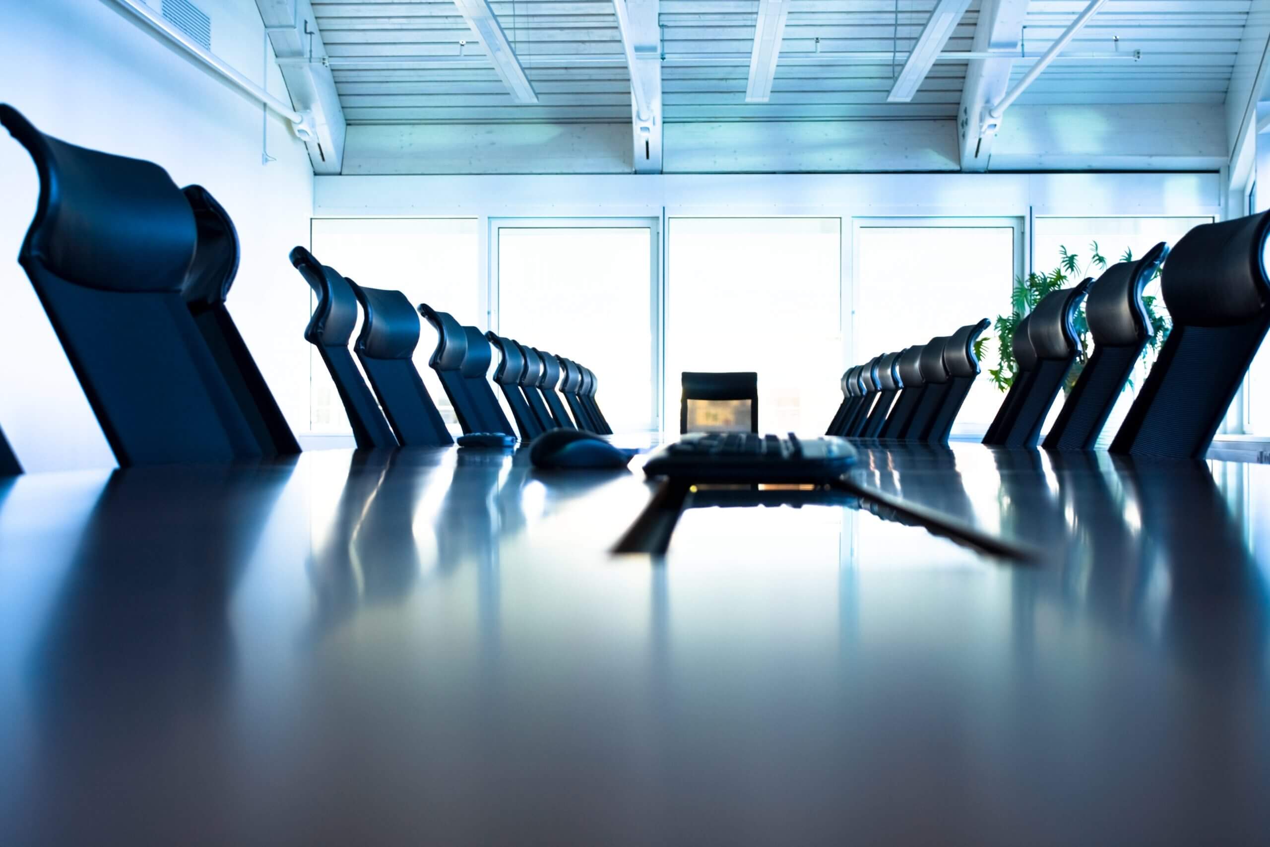 Two people shaking hands across a conference table