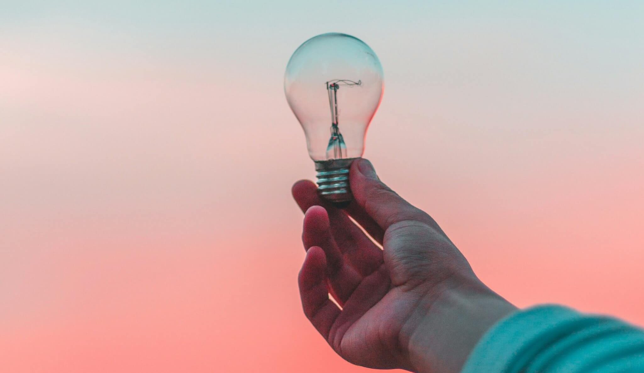 Glowing lightbulb sketched among ideas on a chalkboard